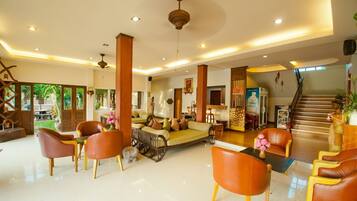 A spacious lobby with a central seating area, a staircase, and a view of the outdoors.