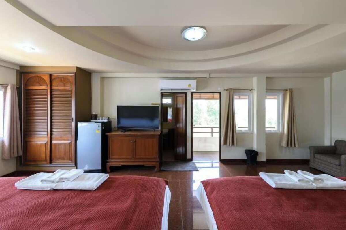 A hotel room with two beds, a television, a refrigerator, and a sliding door leading to a balcony.
