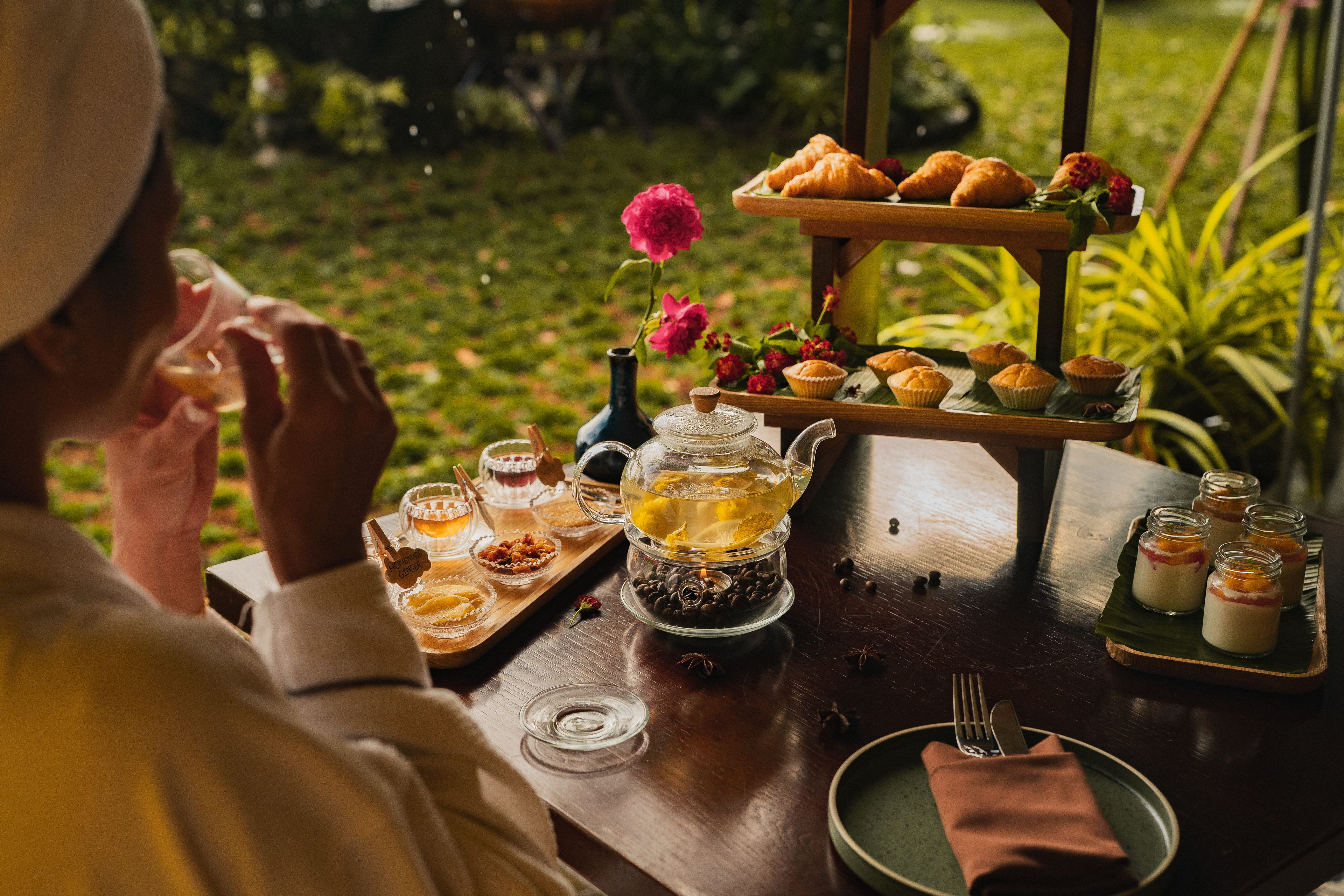 Une table dressée avec des pâtisseries, une théière et de petits pots, qui contiennent probablement du thé ou des desserts.