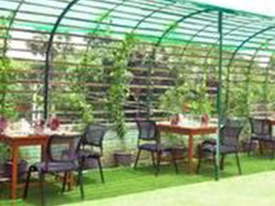 A greenhouse structure with tables and chairs arranged for dining.
