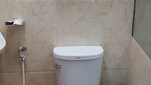 Une salle de bain comprenant des toilettes, un lavabo, un porte-serviettes avec des serviettes pliées et une poubelle.