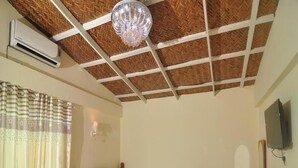 Une chambre à coucher avec un lit en bois, une table de chevet, un téléviseur et un ventilateur de plafond.