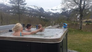 A hot tub with three people in it, surrounded by a natural landscape with mountains and trees. - Voss fjellstove Rongastovo (Voss)