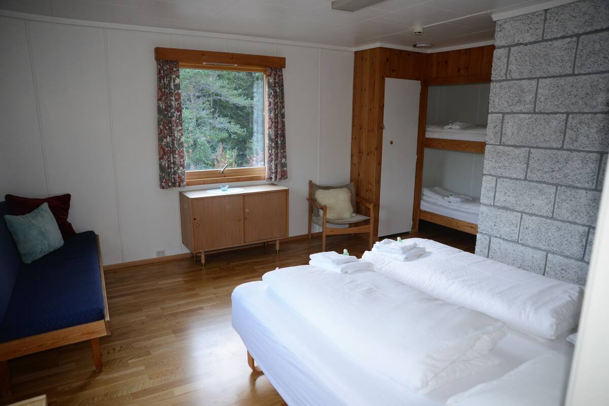 A bedroom with a wooden bed, a wooden desk, a chair, and a wardrobe.