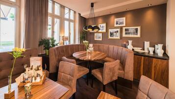 A modern dining area with a round table, cushioned seating, and framed pictures on the wall.