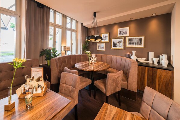 Un comedor moderno con una mesa redonda, asientos acolchados e imágenes enmarcadas en la pared.