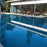 Una piscina al aire libre, sillones reclinables de piscina