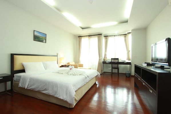 A hotel room with a large bed, a desk, a television, and a view of the outdoors.