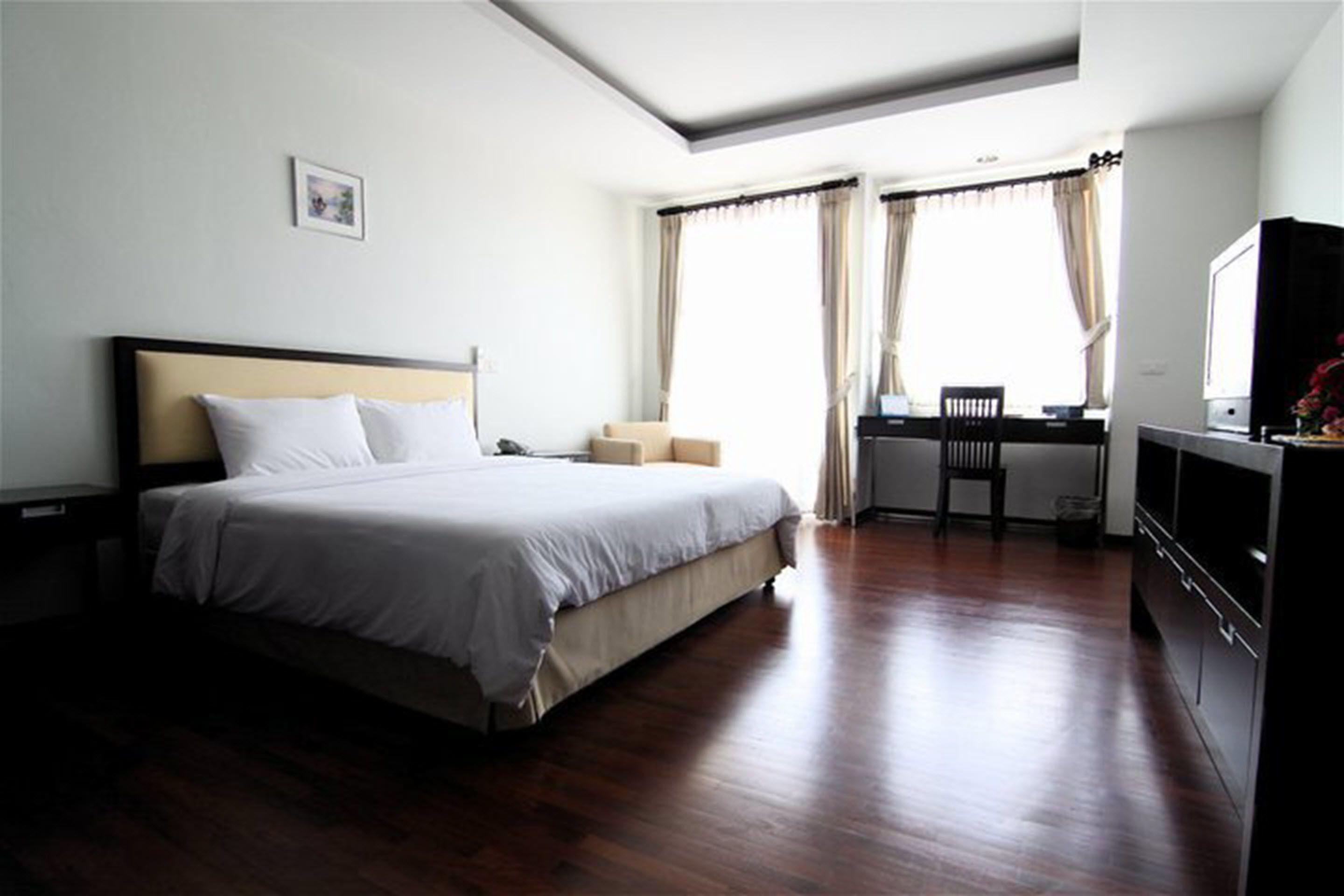 Una habitación de hotel con una cama grande, un escritorio con una silla y un televisor.