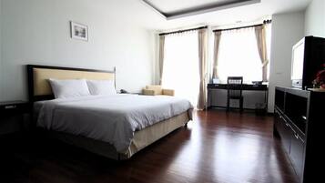 Una habitación de hotel con una cama grande, un escritorio con una silla y un televisor.