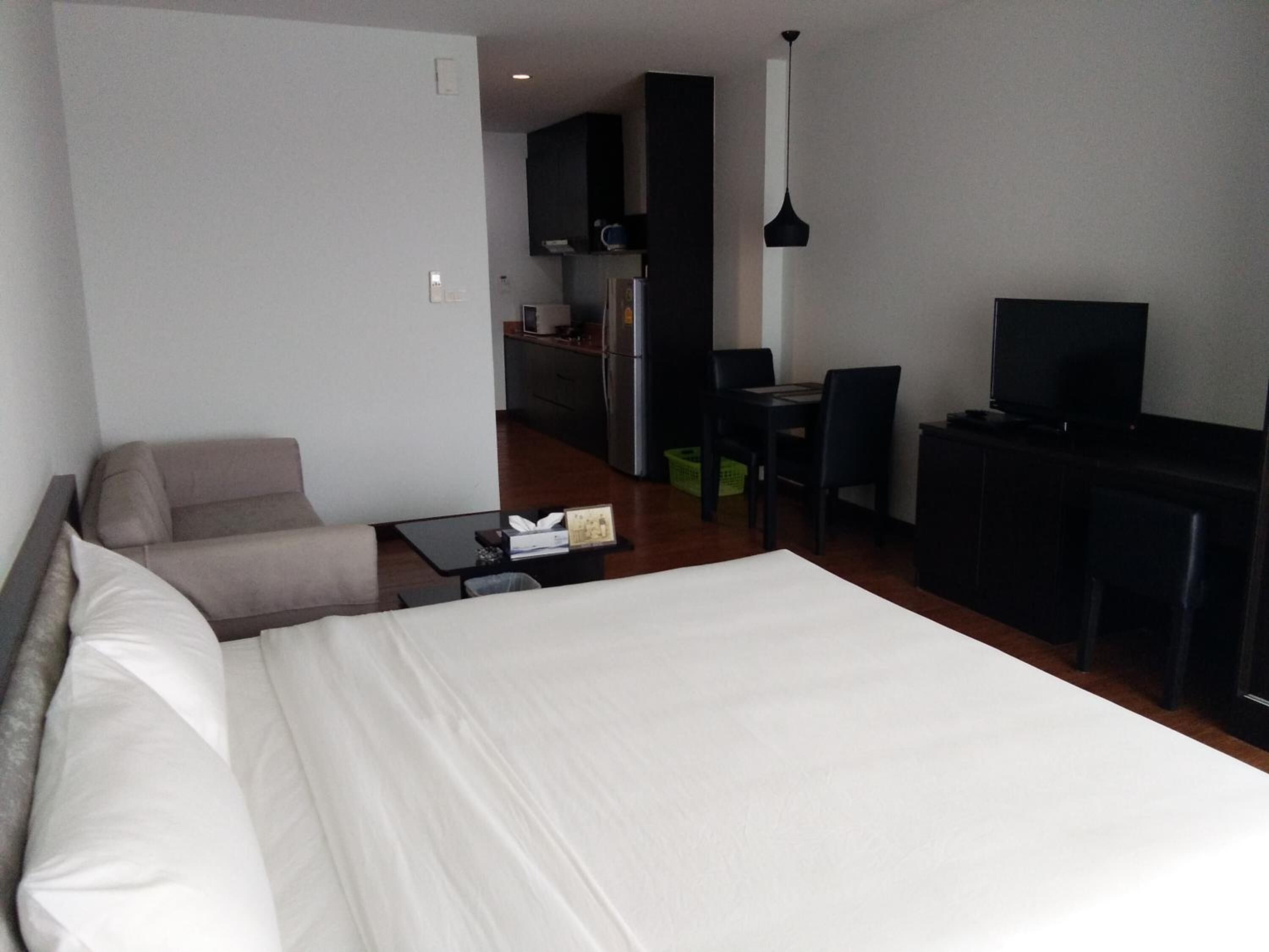 A hotel room with a bed, a desk, a television, and a kitchenette.