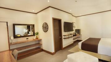A modern bedroom with a bed, a TV, a desk, and a large mirror.