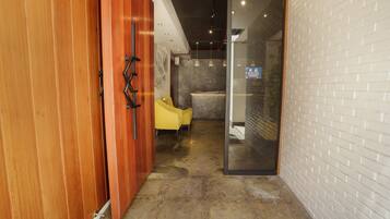 Relax in this stylish room with a glass door leading to a bathroom featuring a shower enclosure and a white tiled wall.