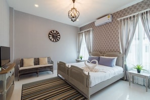 A modern bedroom with a bed, a sofa, a TV, and a clock on the wall. - Wan Arun Houses (Hua Hin)