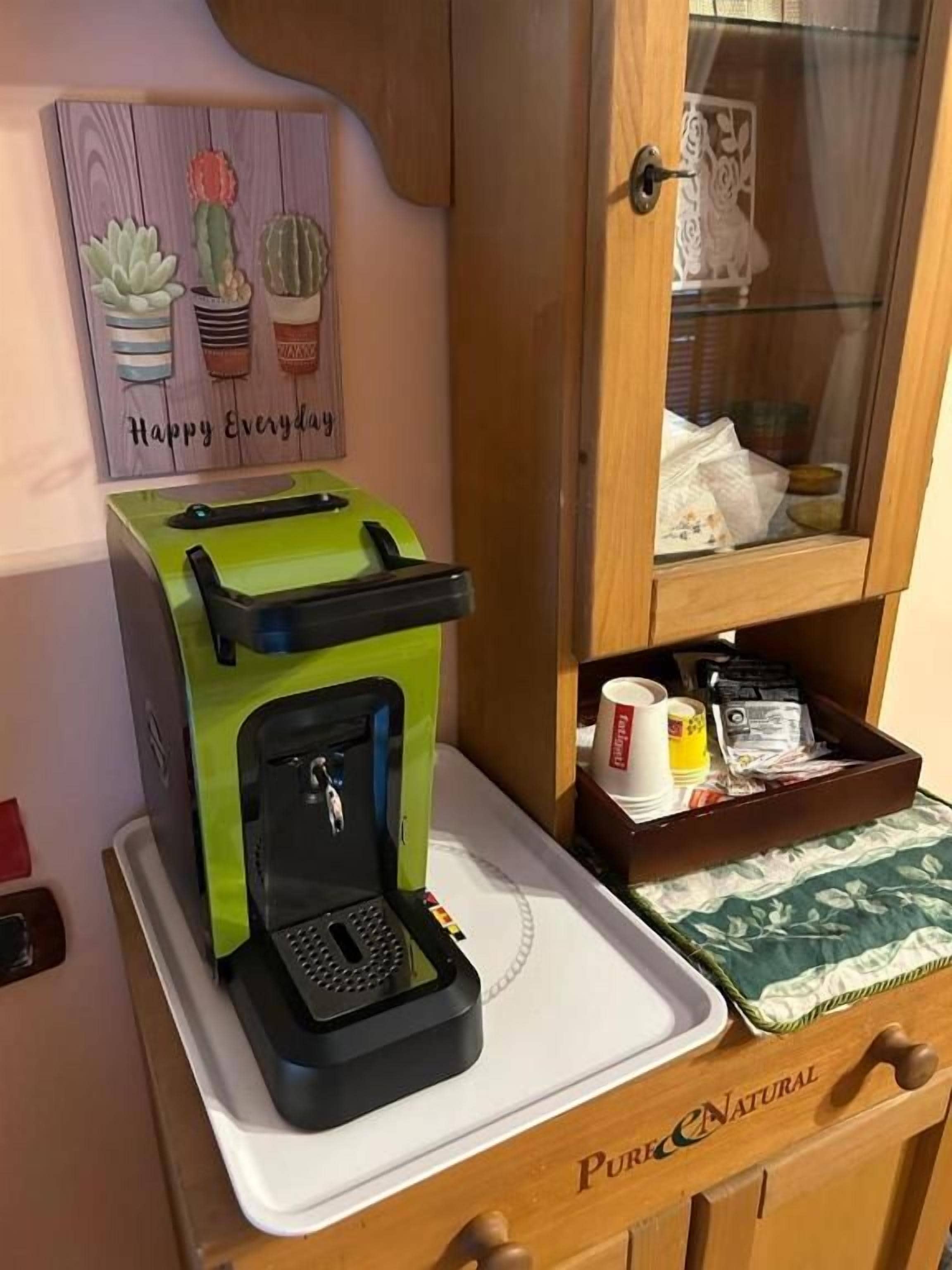 A coffee machine on a tray, a cabinet with a glass door, and a wall decoration with cacti.