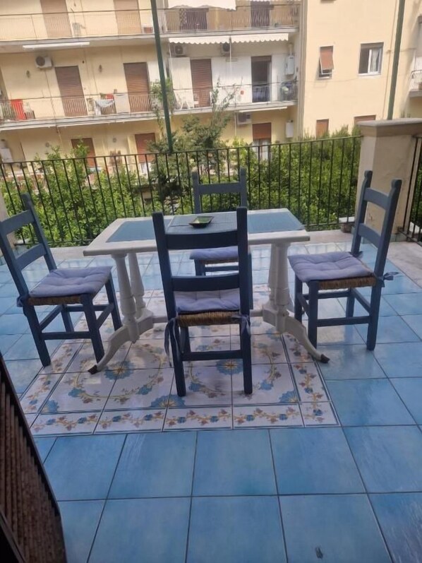 A balcony with a table and chairs, a patterned rug, and a view of a residential building. - B&B Il Nido (Portici)