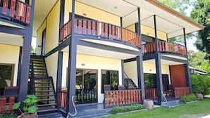 Un edificio de varios pisos con balcones, una escalera y un espacio exterior cubierto.