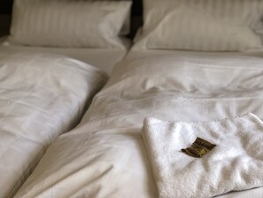 A neatly made bed with white linens and a visible tag on the pillow. - Hotel Junkerhaus (Bad Salzuflen)