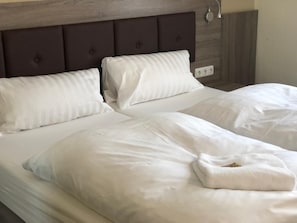 Una cama doble con ropa de cama blanca y un cabecero oscuro.