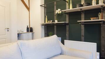 A modern living room with a white sofa, a radiator, and shelves with decorative items.