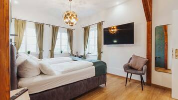Un dormitorio con cama, una silla, un televisor y un espejo.