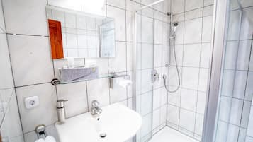Un bagno moderno con cabina doccia in vetro, un lavandino bianco e uno specchio con cornice in legno.