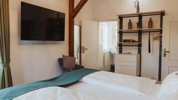 A hotel room with a bed, a television mounted on the wall, a wardrobe, and a mirror.
