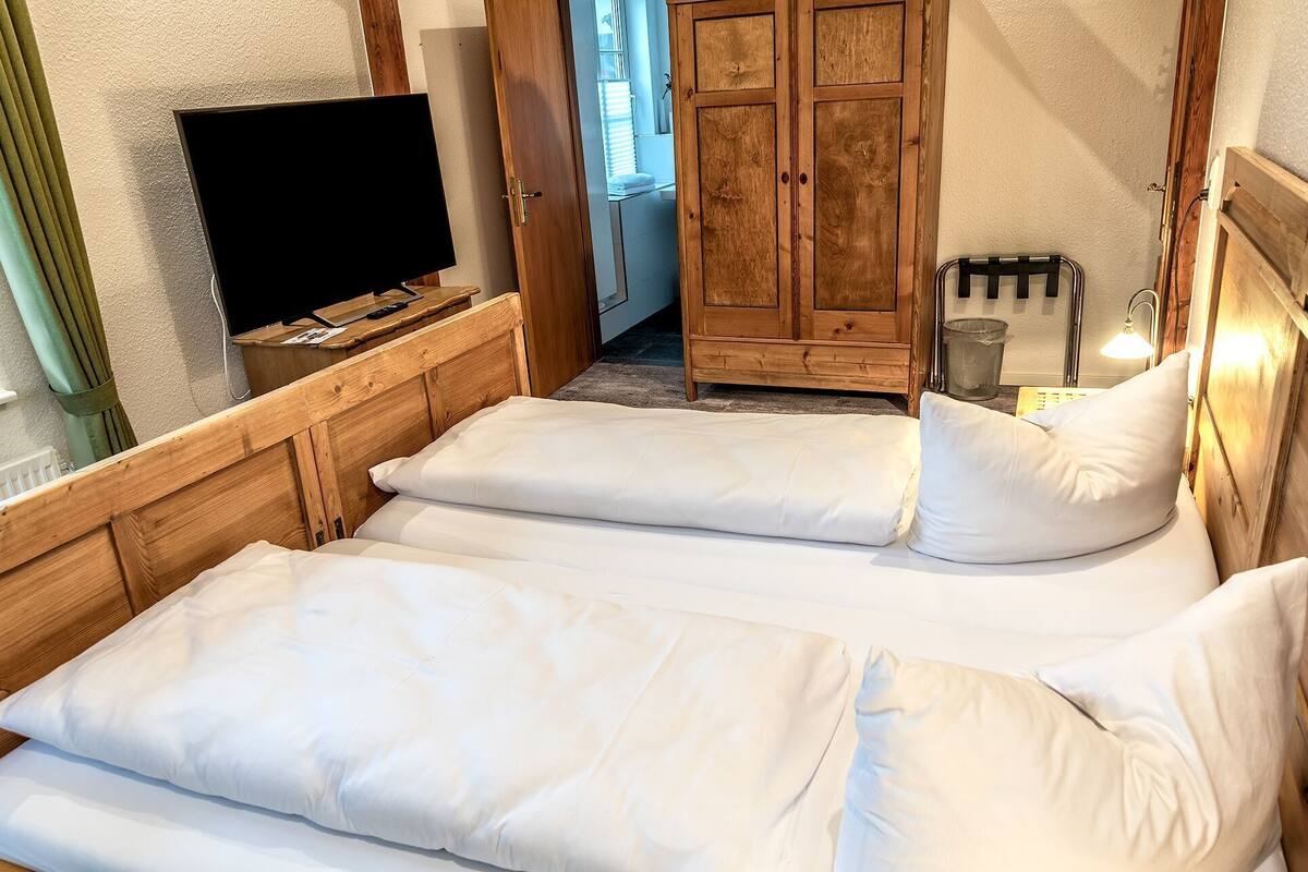 Un dormitorio con dos camas, un armario de madera, un televisor y una mesita.