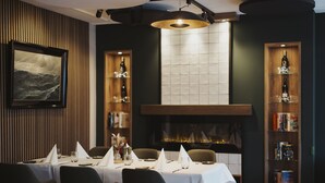 Un coin repas agrémenté d’une cheminée, de boiseries et d’une bibliothèque.