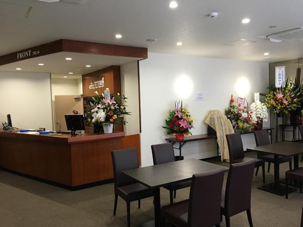 Zona de recepción de un hotel con un escritorio de madera, sillas y un letrero que indica la recepción.
