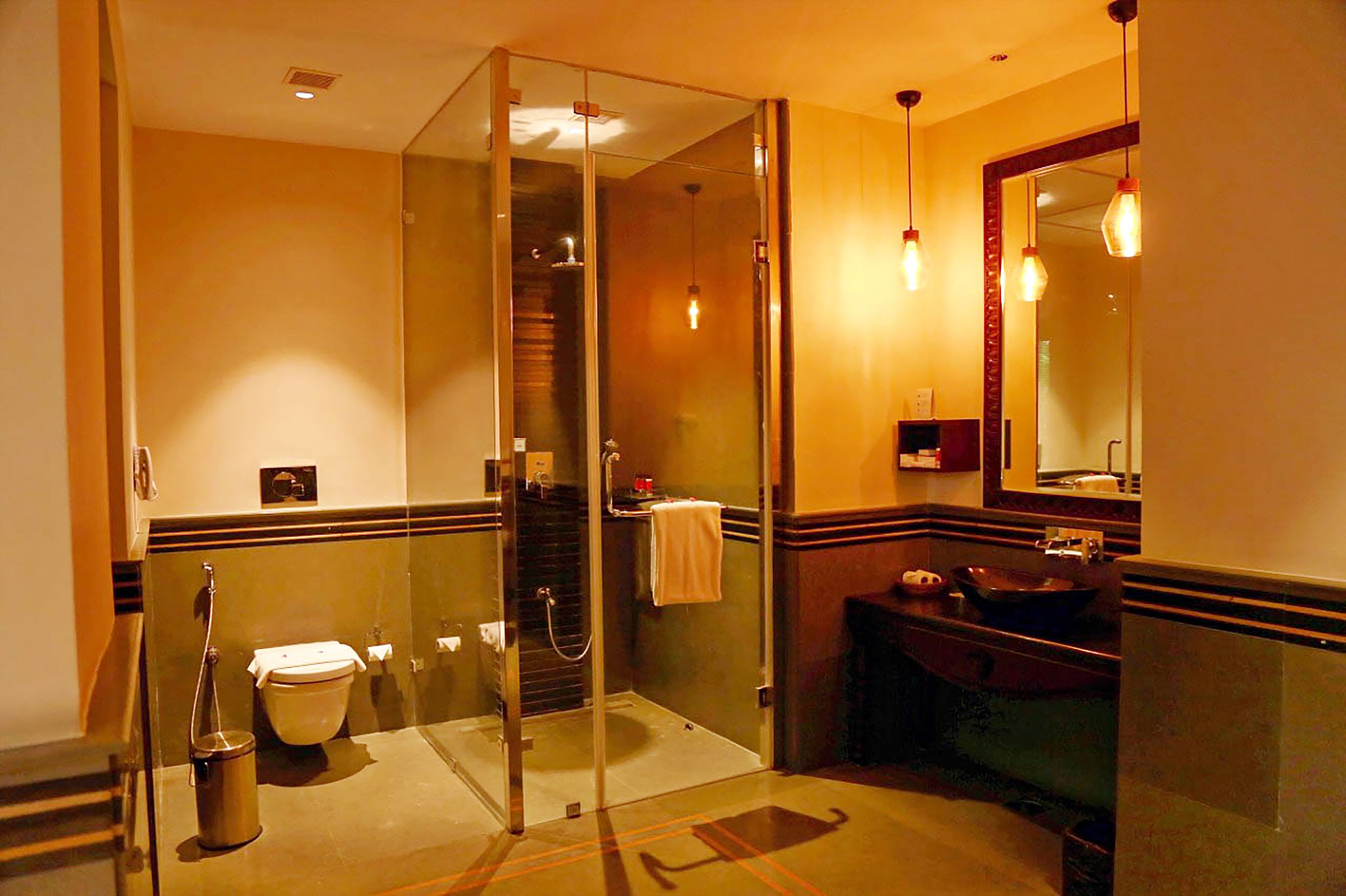 Un baño moderno con ducha envuelta en vidrio, inodoro, lavamanos y espejo.