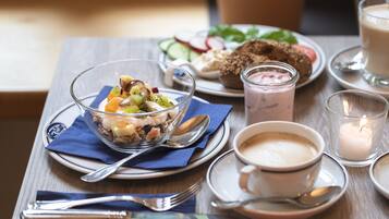 Ein Tisch mit einer Mahlzeit bestehend aus Obstsalat, Brot und einer Tasse Kaffee.