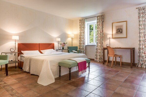 A bedroom with a bed, bedside tables, a desk, a chair, and a window with curtains. - Burg Heimerzheim (Swisttal)
