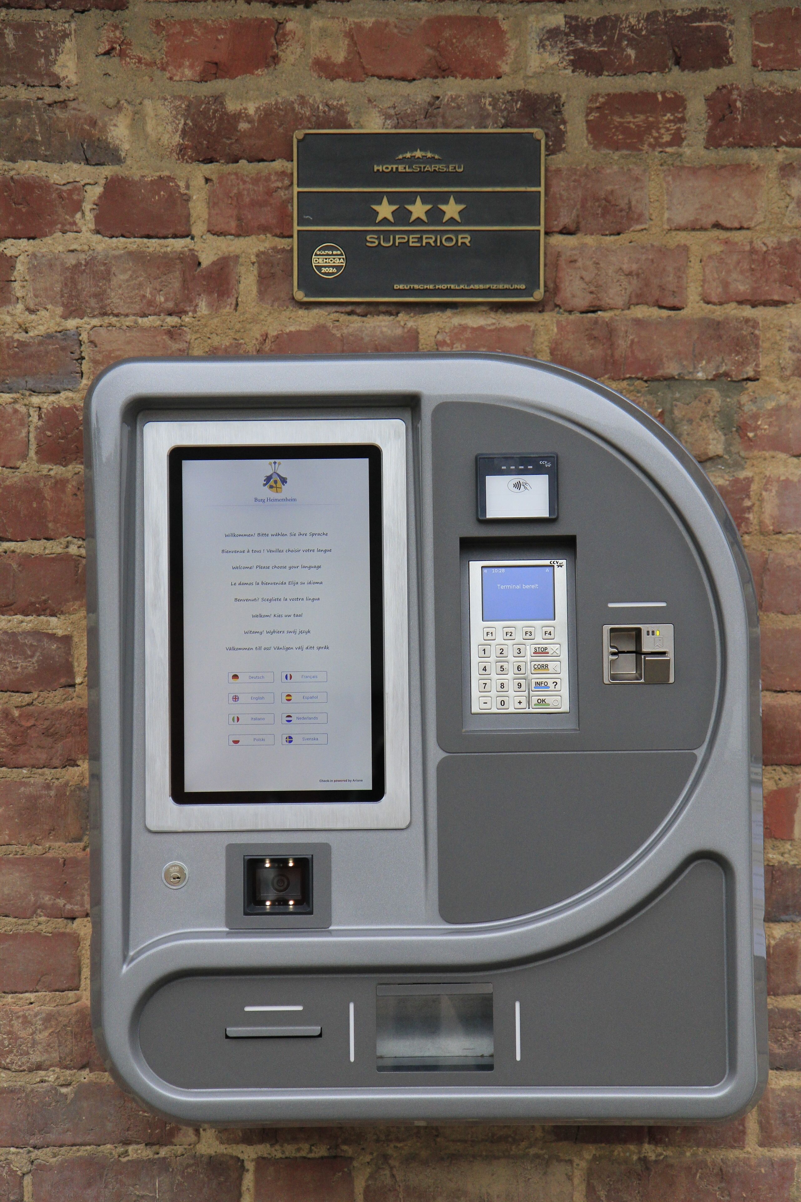 Bedieningspaneel in een hotelkamer met een digitaal scherm, een keypad en een klein beeldscherm.