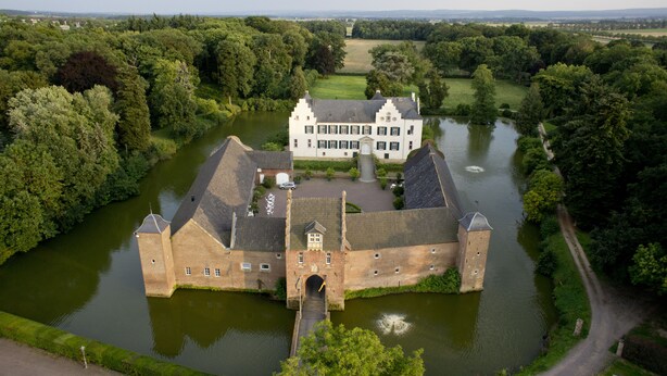 A historic building with a moat, surrounded by lush greenery and a river. - Burg Heimerzheim (Swisttal)