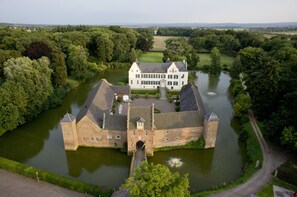 A historic building with a moat, surrounded by lush greenery and a river. - Burg Heimerzheim (Swisttal)