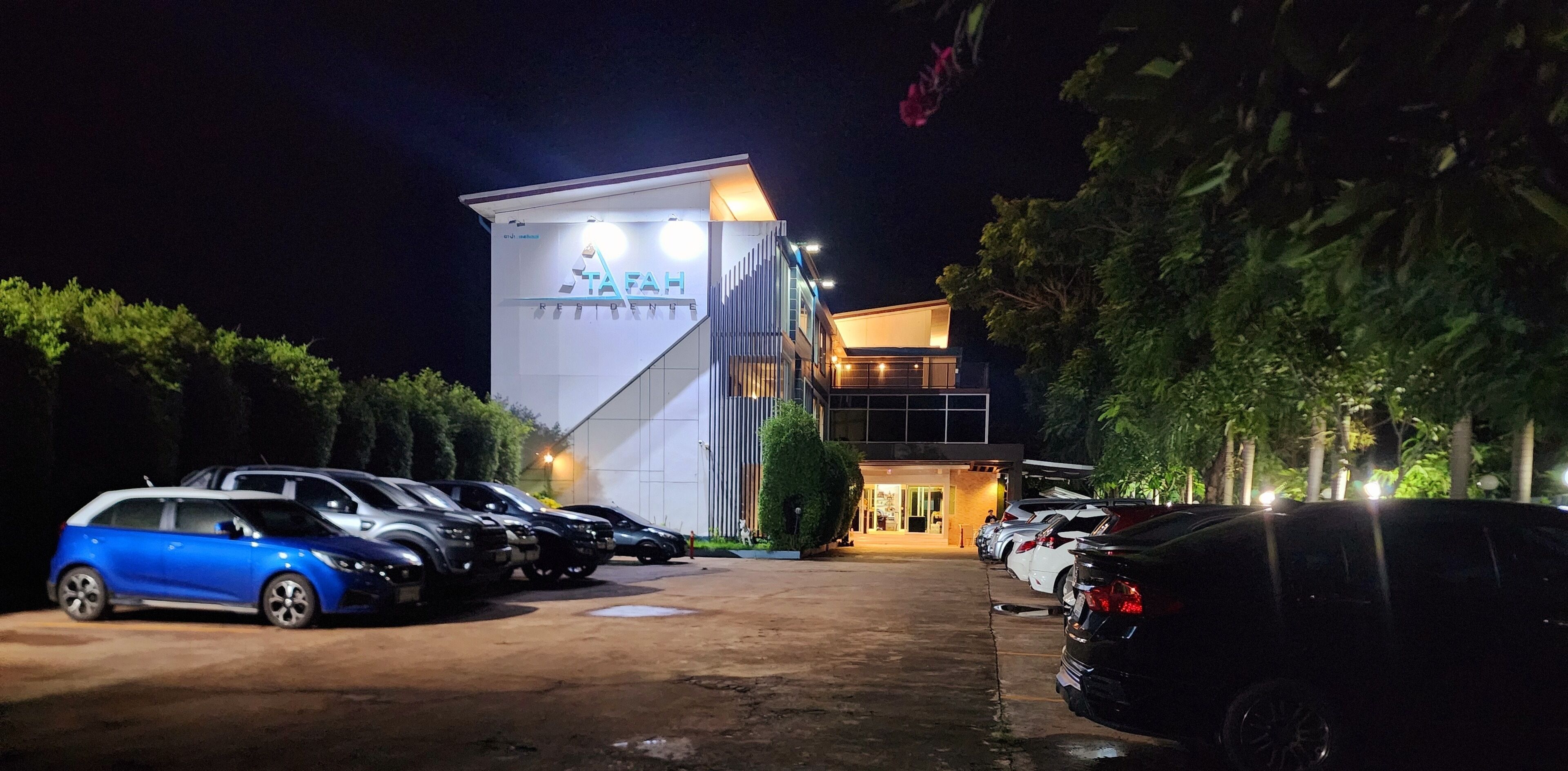 A parking lot with several cars parked in front of a building with a sign that reads "TAFAH".