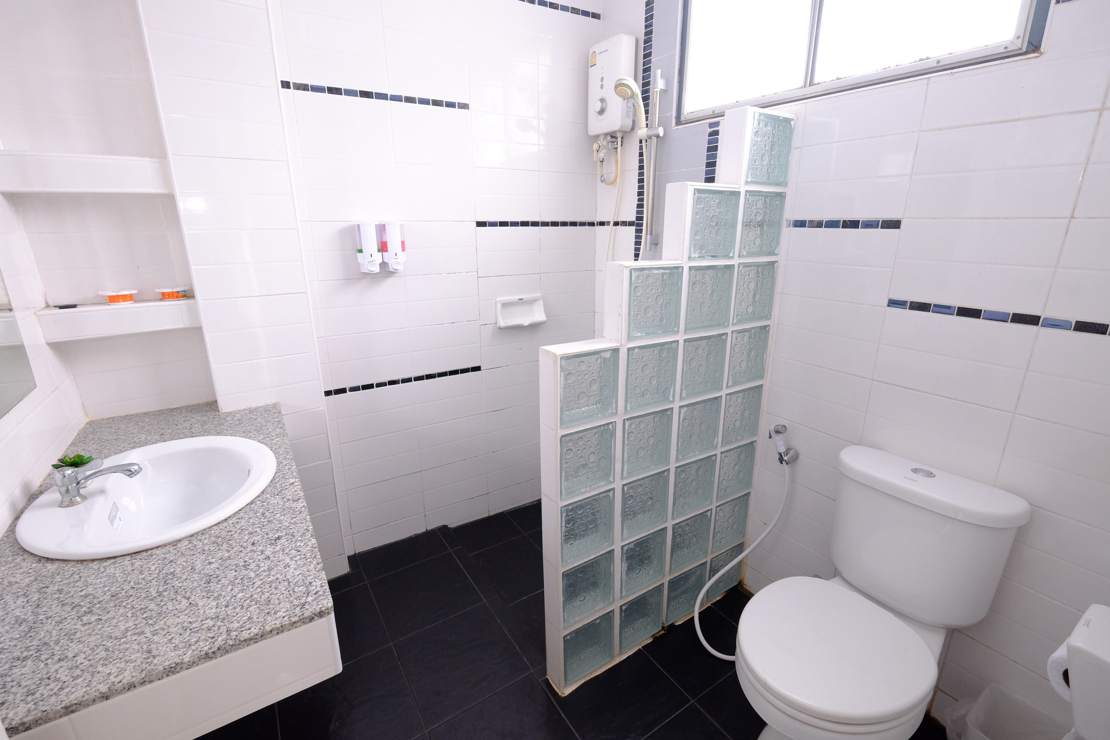 Een badkamer met een wit wastafelmeubel, een toilet en een douchecabine met glazen wanden.