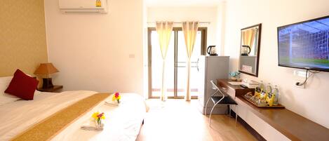 A hotel room with a bed, a desk, a TV, and a window with curtains.