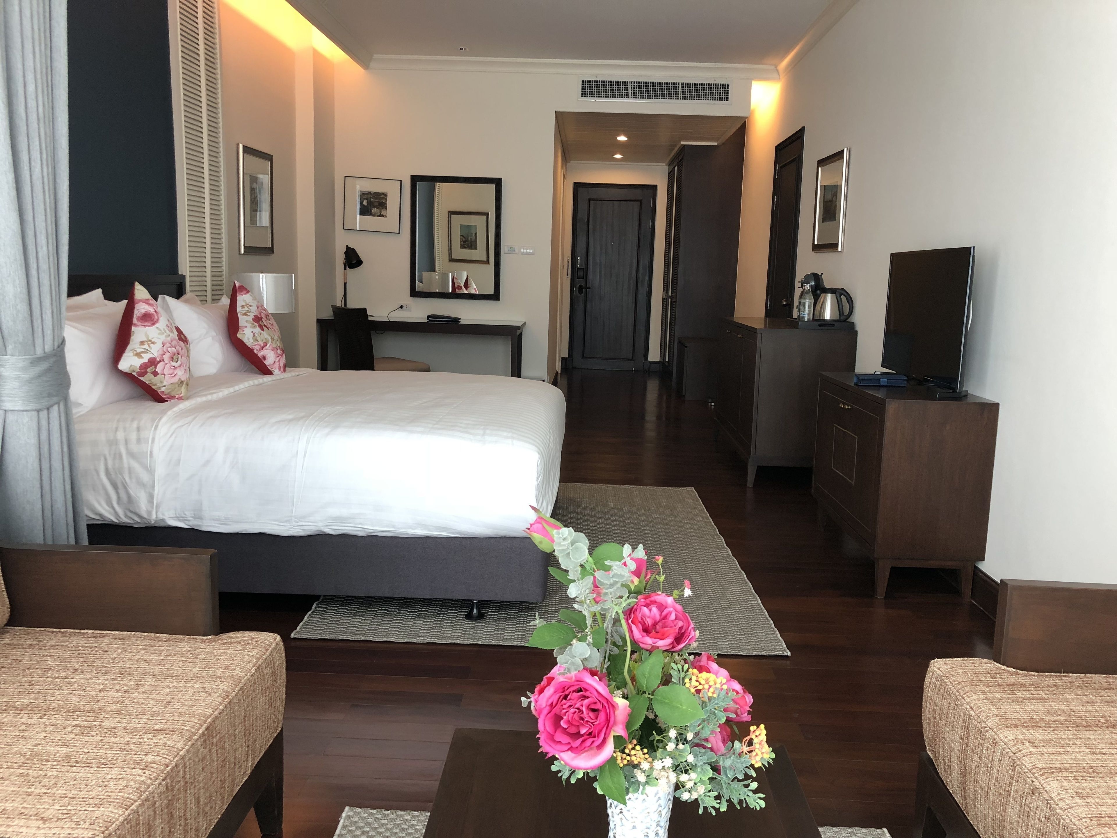 Een hotelkamer met een groot bed, een bureau, een televisie en een koffieapparaat.