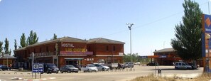 A building with a sign reading "HOSTAL LOS CHOPOS" and a "BAR" sign below it. There are cars parked in front and a street lamp nearby. - Hostal Restaurante Los Chopos (Osorno)