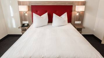 Habitación empresarial individual | Edredón, minibar, caja de seguridad en la habitación y escritorio