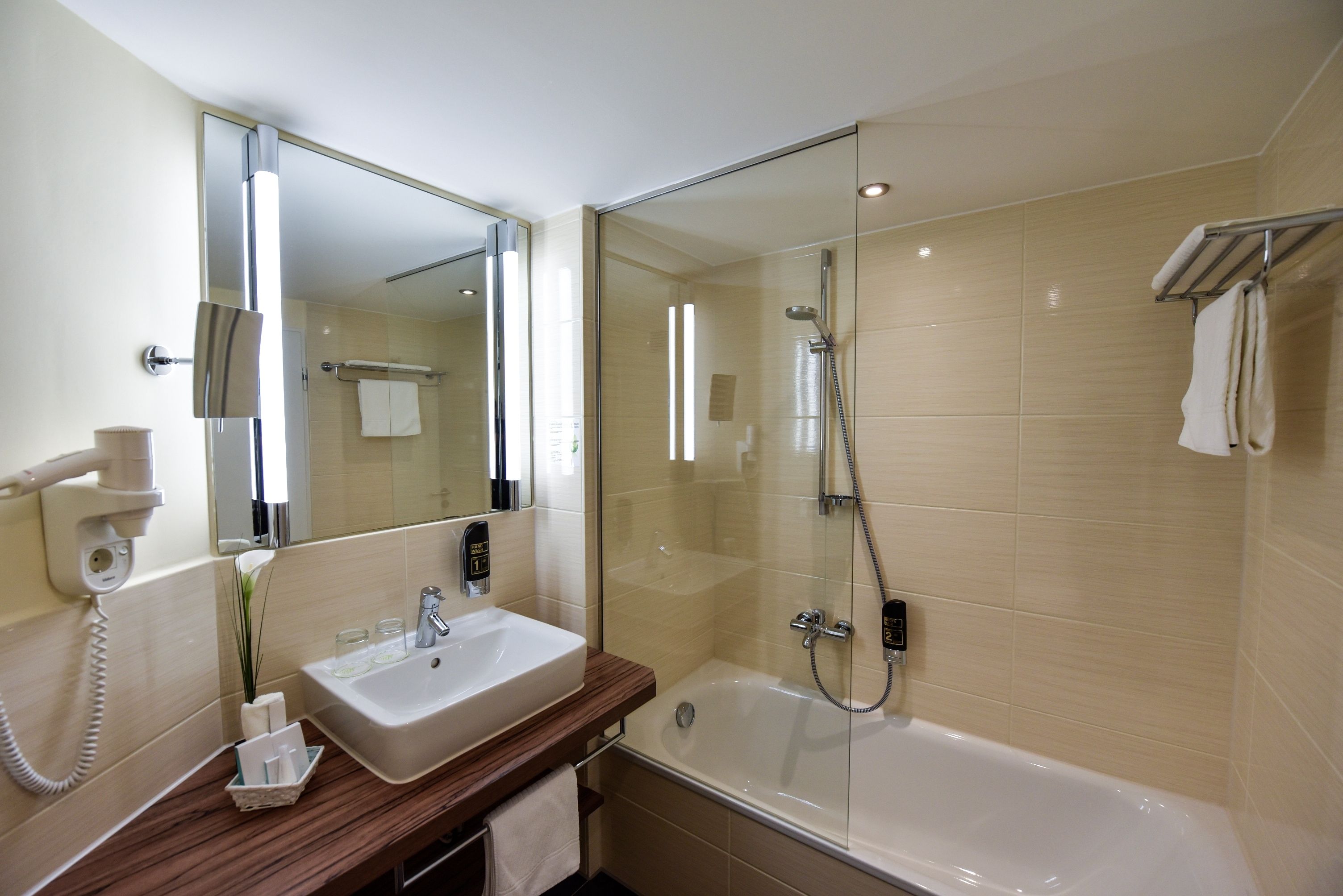 A modern bathroom with a glass-enclosed shower, a sink with a mirror, and a towel rack.