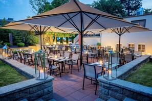 An outdoor patio with multiple tables and chairs, large umbrellas, and lanterns. - Hotel Vorfelder (Walldorf)