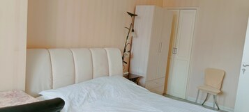 Un dormitorio con cama, armario, silla y lámpara.