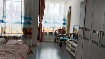 A hotel room with a bed, a desk with a chair, a TV, and a wardrobe.