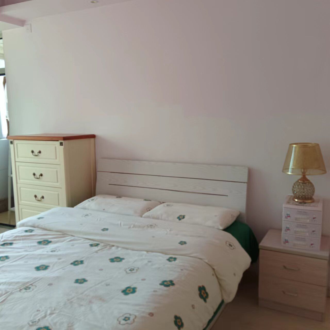 Un dormitorio con cama, mesita de noche con lámpara, cómoda y espejo.