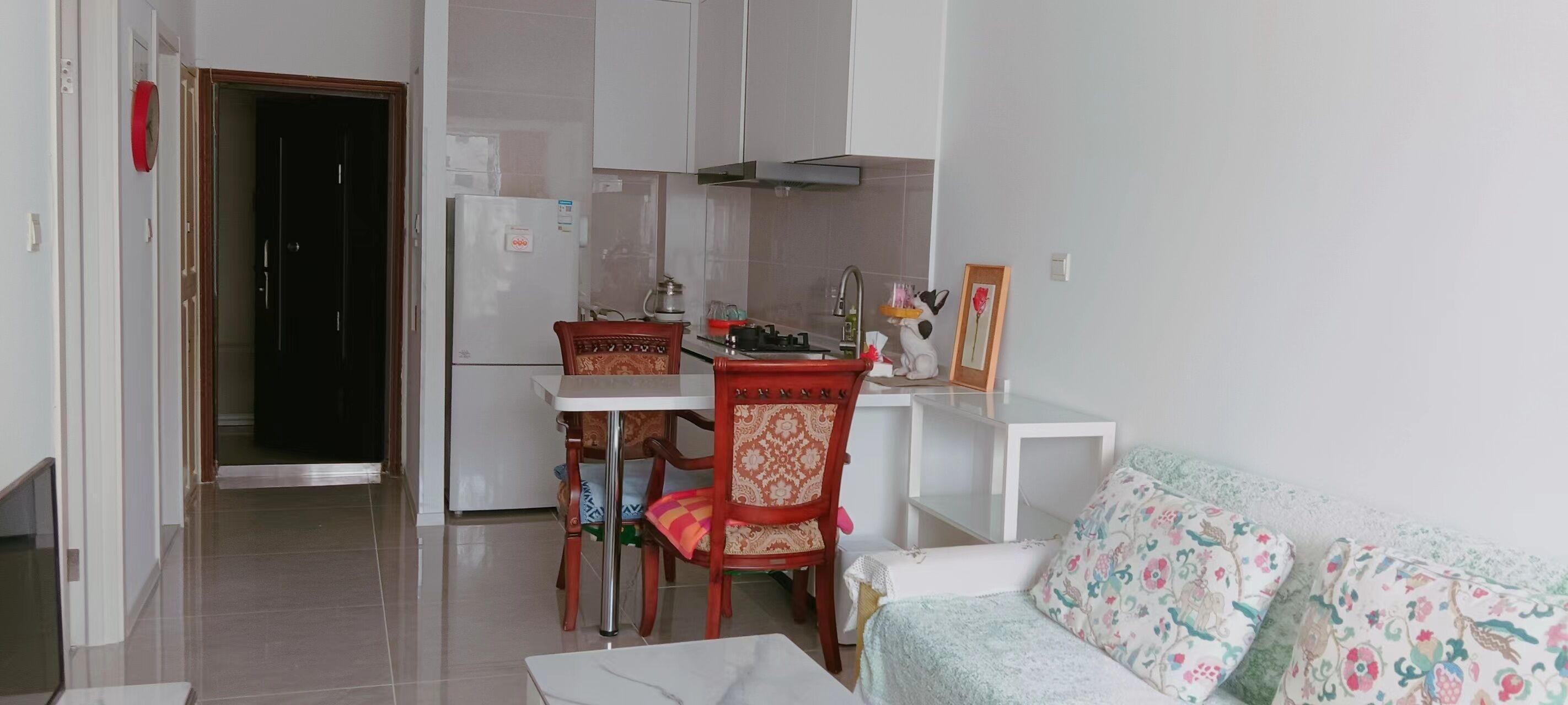 Ett kompakt bostadsutrymme med ett litet kök, en matplats med bord och stolar samt en soffa.