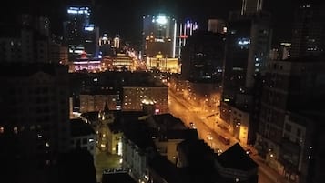 Un paisaje urbano nocturno con edificios iluminados y una calle concurrida.