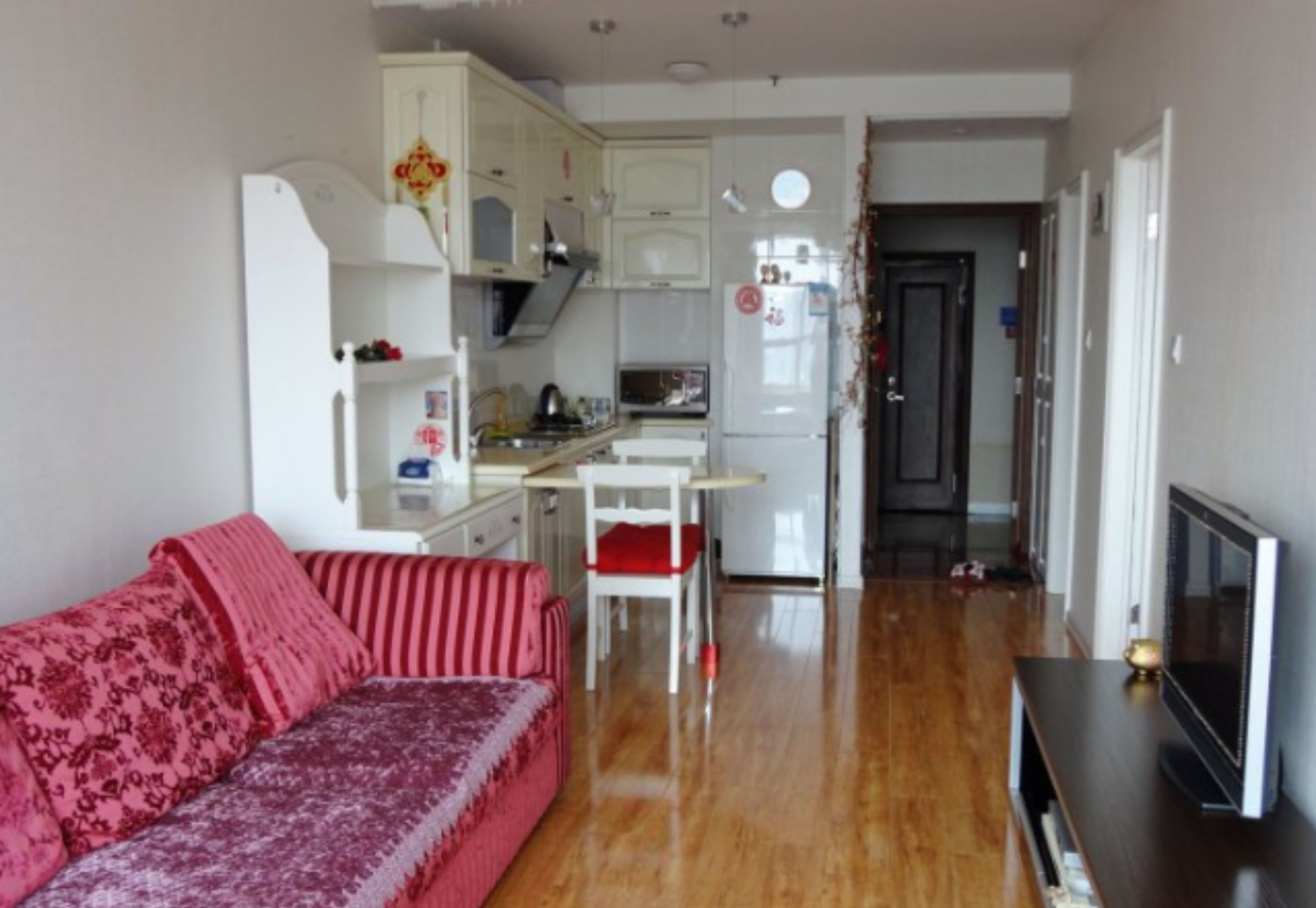 Un espacio habitable compacto con kitchenette, un sofá, una mesa de comedor y un televisor.